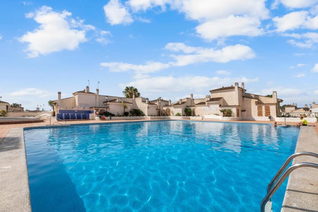 a swimming pool with blue water in front of houses at Casa Varadero in Santa Pola