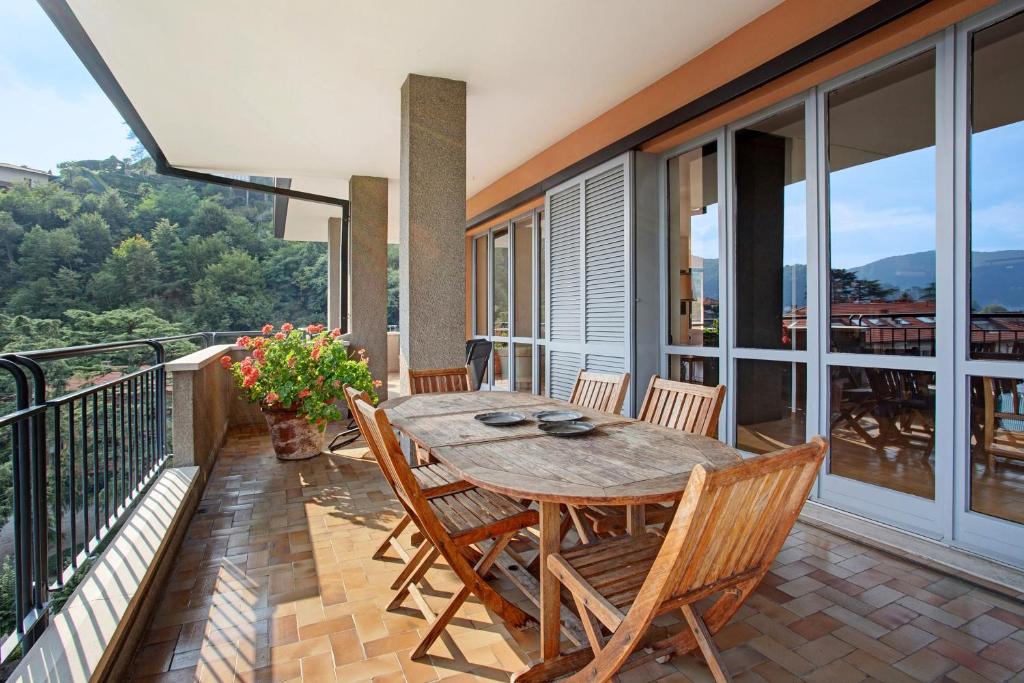 a patio with a wooden table and chairs on a balcony at Appartamento Il Parco Cernobbio in Cernobbio
