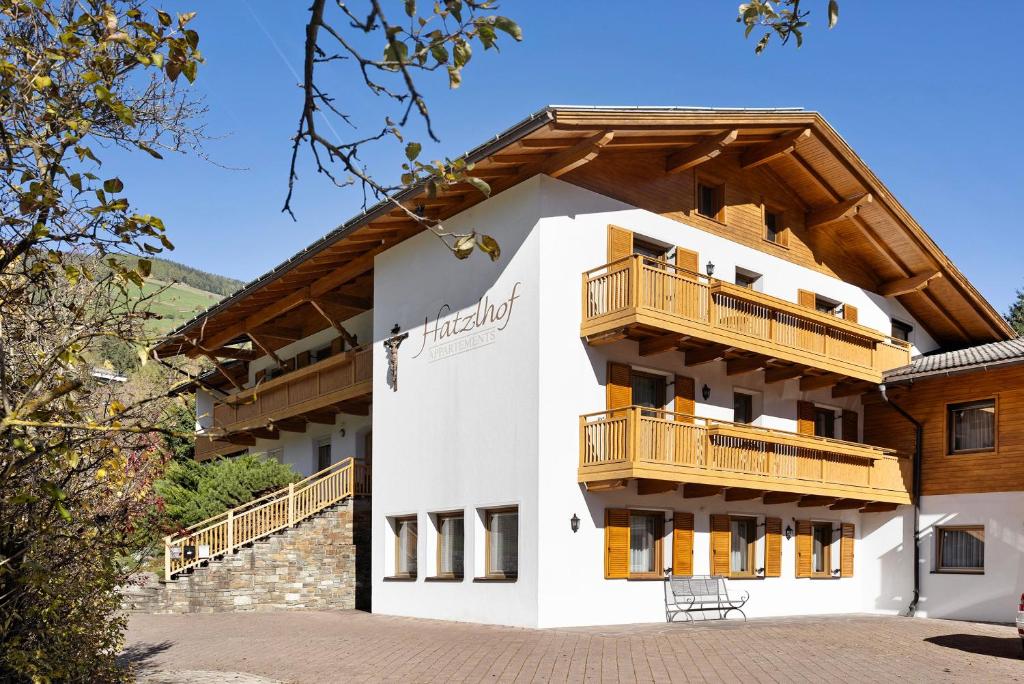 a white building with wooden balconies on it at Hatzlhof Appartements in Vipiteno