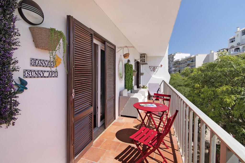 a balcony with two red chairs and a table at Hanna's Sunny Apartment in Albufeira