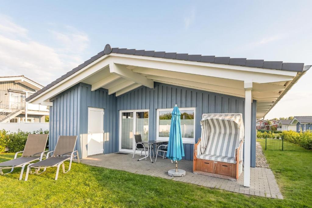a blue shed with a table and chairs on a lawn at Ferienhaus Stockente in Dagebüll