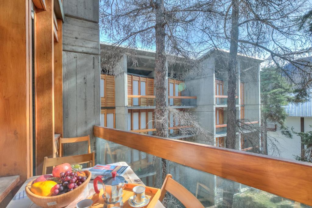 a table with a bowl of fruit on a balcony at Slalom 73 few Steps from Skiing - Happy Rentals in Bardonecchia