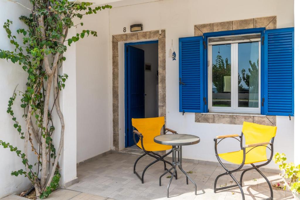 a patio with yellow chairs and a table and a window at Perasma Studios 8 in Kipri