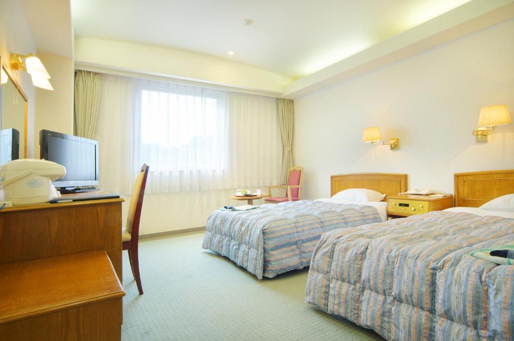 a hotel room with two beds and a television at New Royal Hotel Shimanto in Shimanto