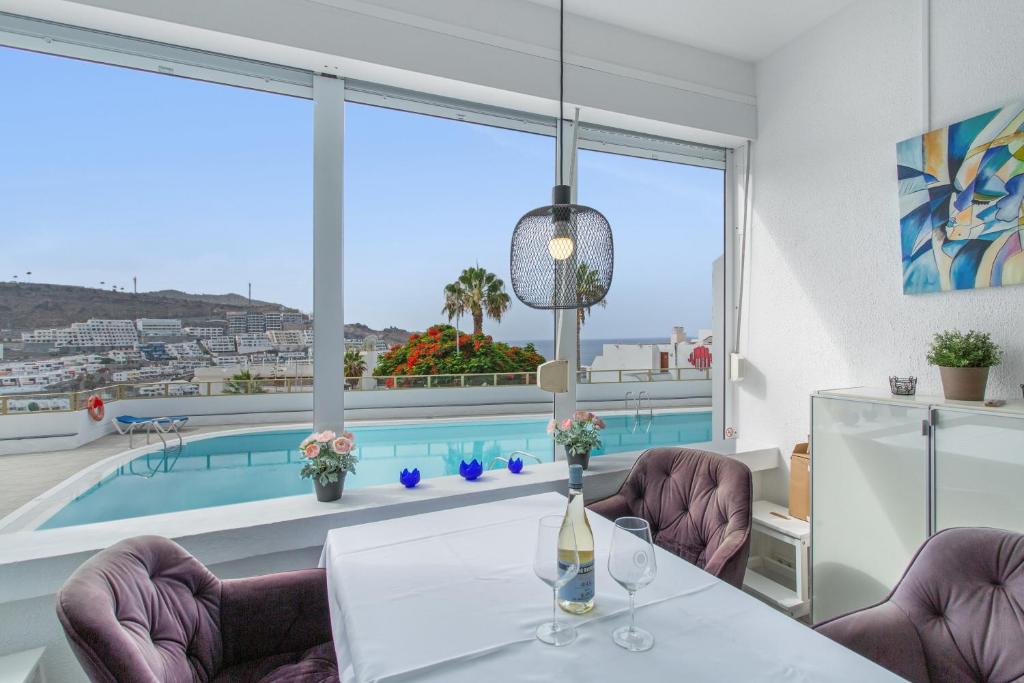 a dining room with a table and chairs and a pool at Vistas al atlantico in Puerto Rico de Gran Canaria