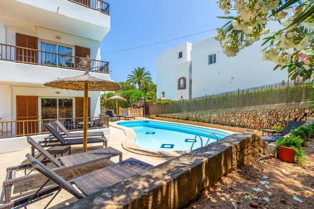 a villa with a swimming pool and two chairs and an umbrella at Gran Sol Family 7 in Felanitx