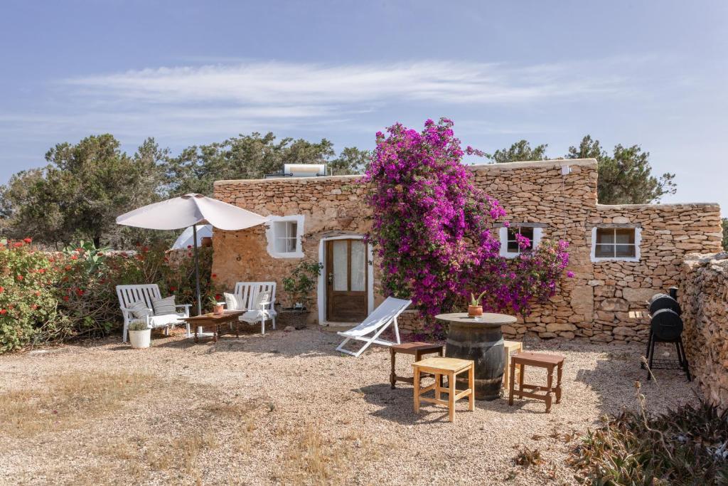 a stone house with a table and chairs and flowers at Can Xicu in Illes Balears