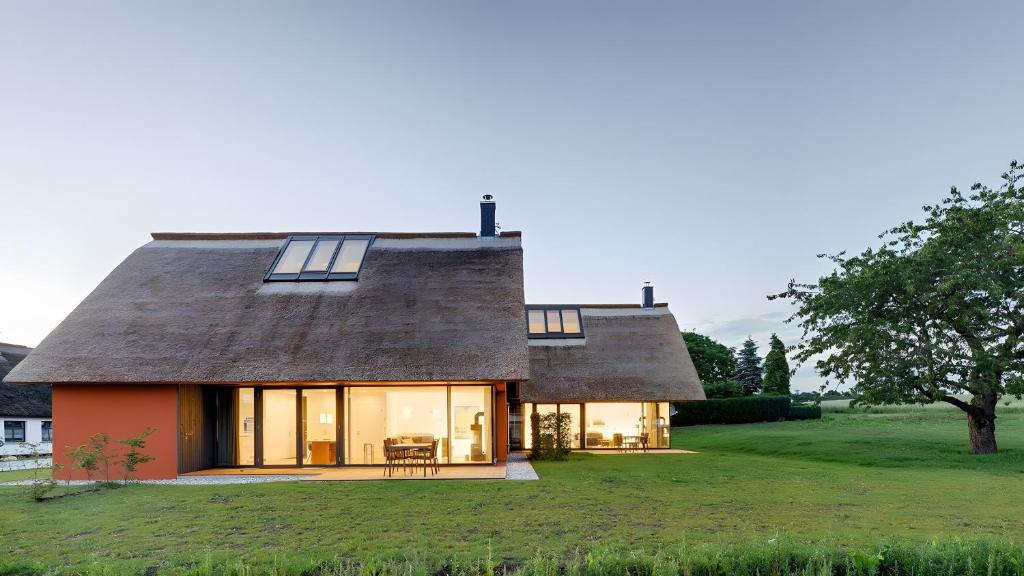 a house with a thatched roof on a green field at Ferienhaus Wreechen 25, Haus 1 in Putbus