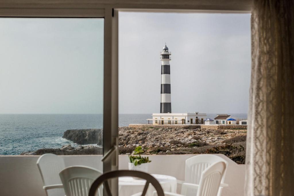 a lighthouse view from a room with a table and chairs at El Faro 8 in Cala en Bosc