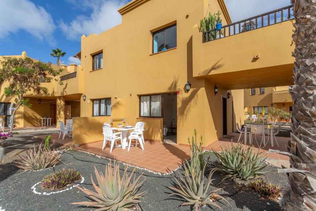 a yellow house with a patio with a table and chairs at Casa Piña Colada in Corralejo