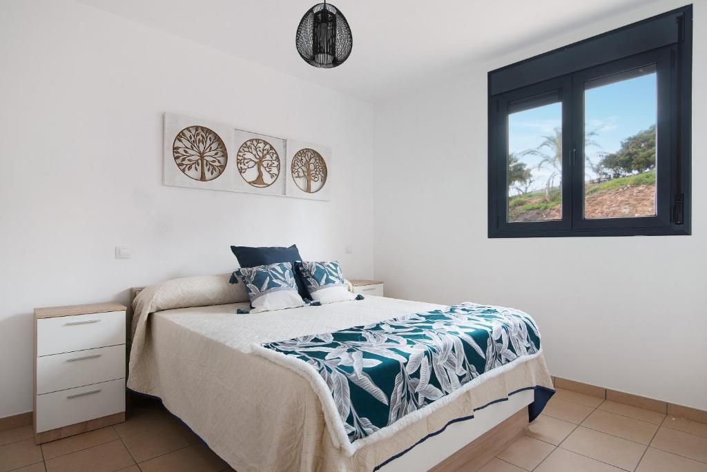 a white bedroom with a bed and a window at El Refugio in Sardina