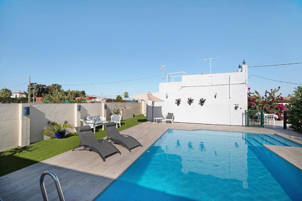 a swimming pool with a table and chairs next to a house at Beautiful Traditional House in Chipiona