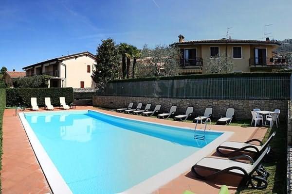 una piscina con tumbonas y una casa en Casa Orchidea Apartments, en Torri del Benaco