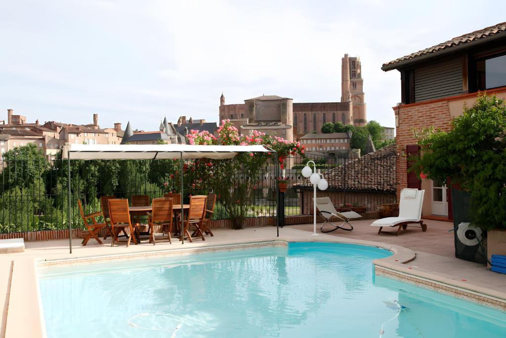 a swimming pool with a table and chairs and an umbrella at La Chambre de Cécile in Albi