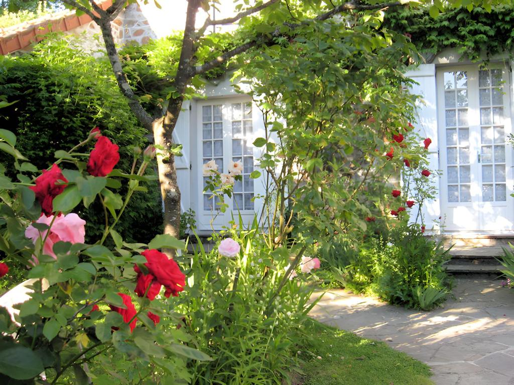 a garden with red roses and a white house at Studio chambre d'hôte in Panazol