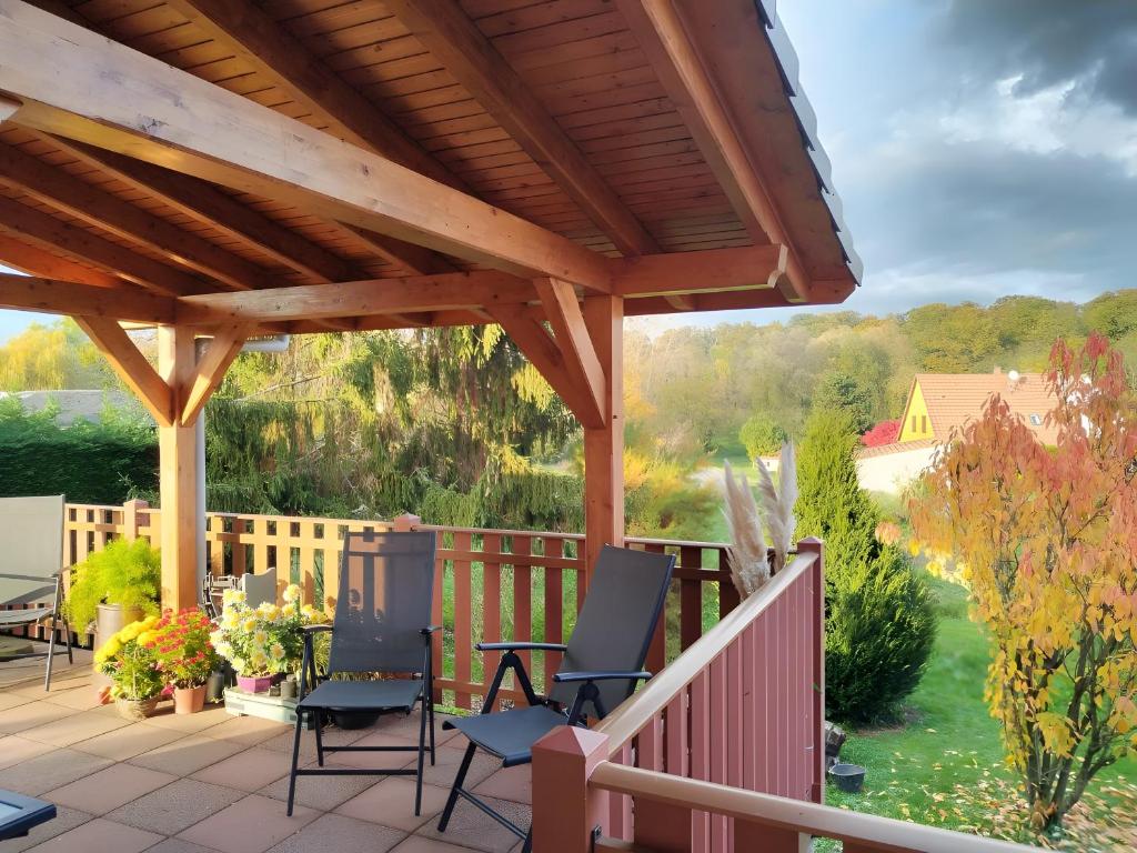 a deck with chairs and a wooden pergola at Chambres D'hôtes - Suite Pampas in Geiswiller