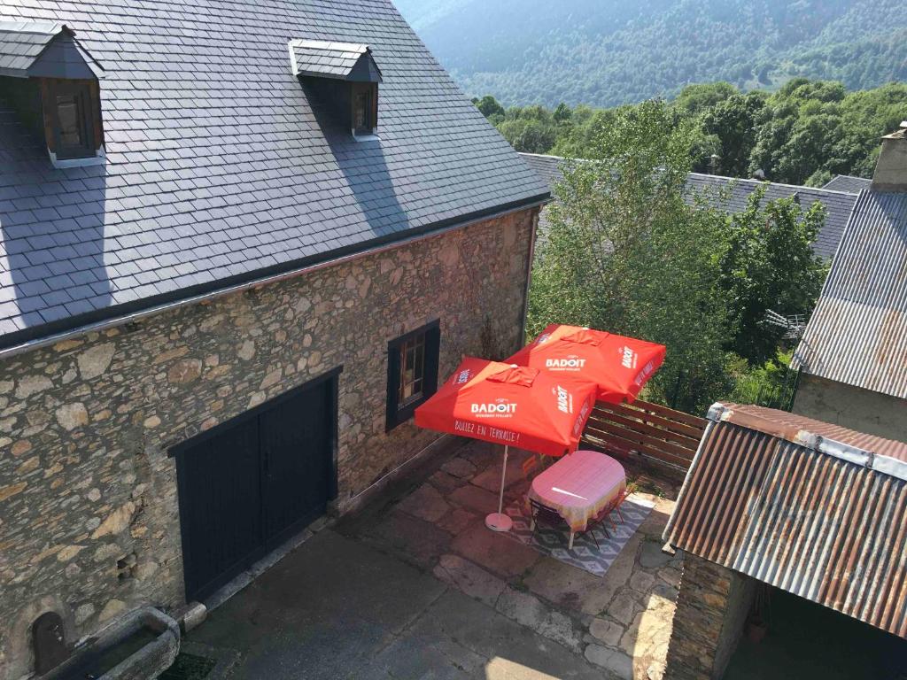 a patio with two red umbrellas and a bench at Chaleureuse Maison de Montagne in Garin