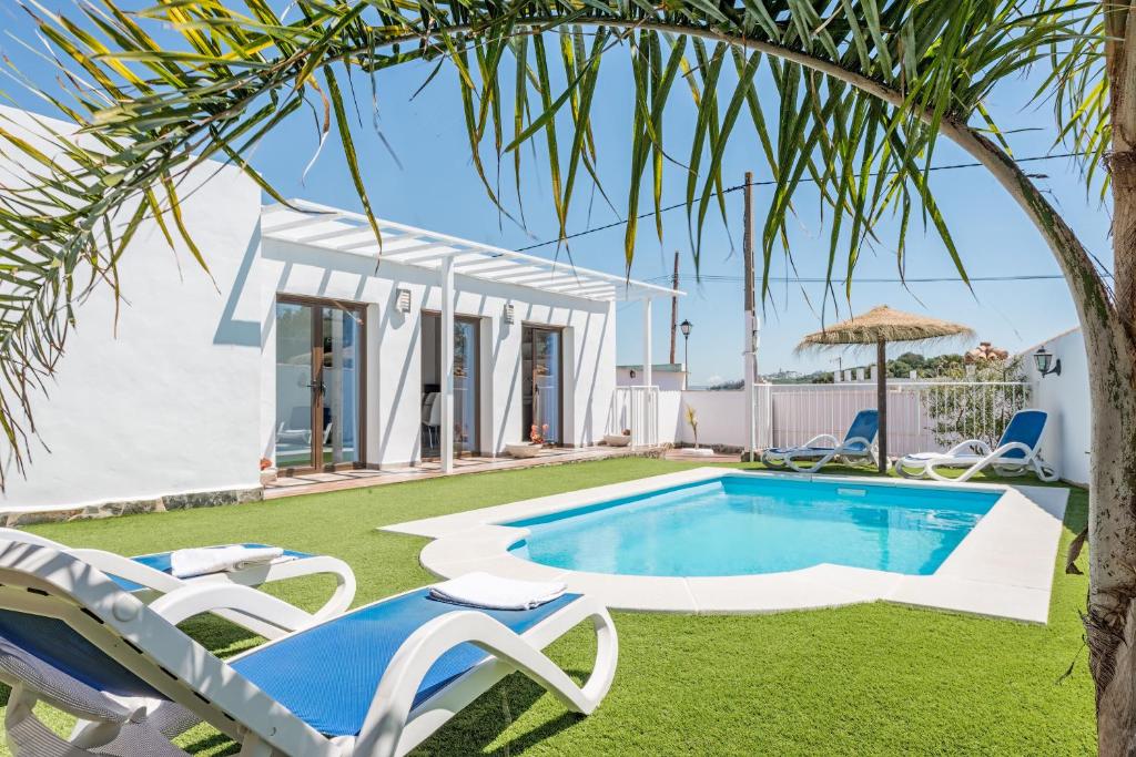 a villa with a pool and a palm tree at Casa Capricho in Vejer de la Frontera