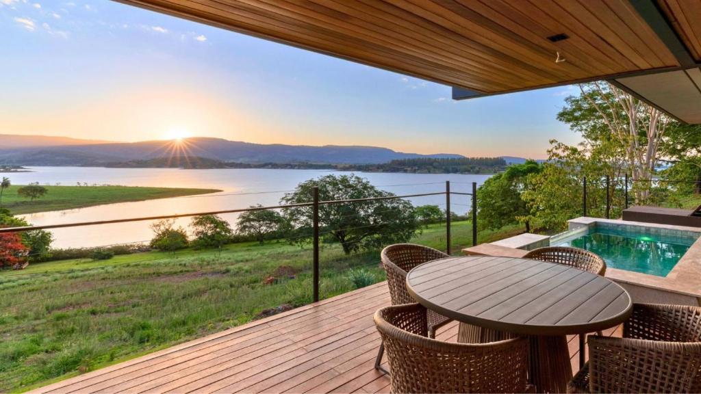 a deck with a table and chairs and a view of the water at Morro Redondo - Bangalôs com vista do lago e da serra in CÃ¡ssia