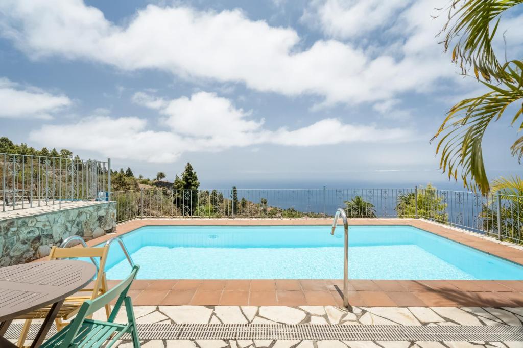 a swimming pool with a table and chairs and a view of the ocean at Casa Juliana Tijarafe in Tijarafe