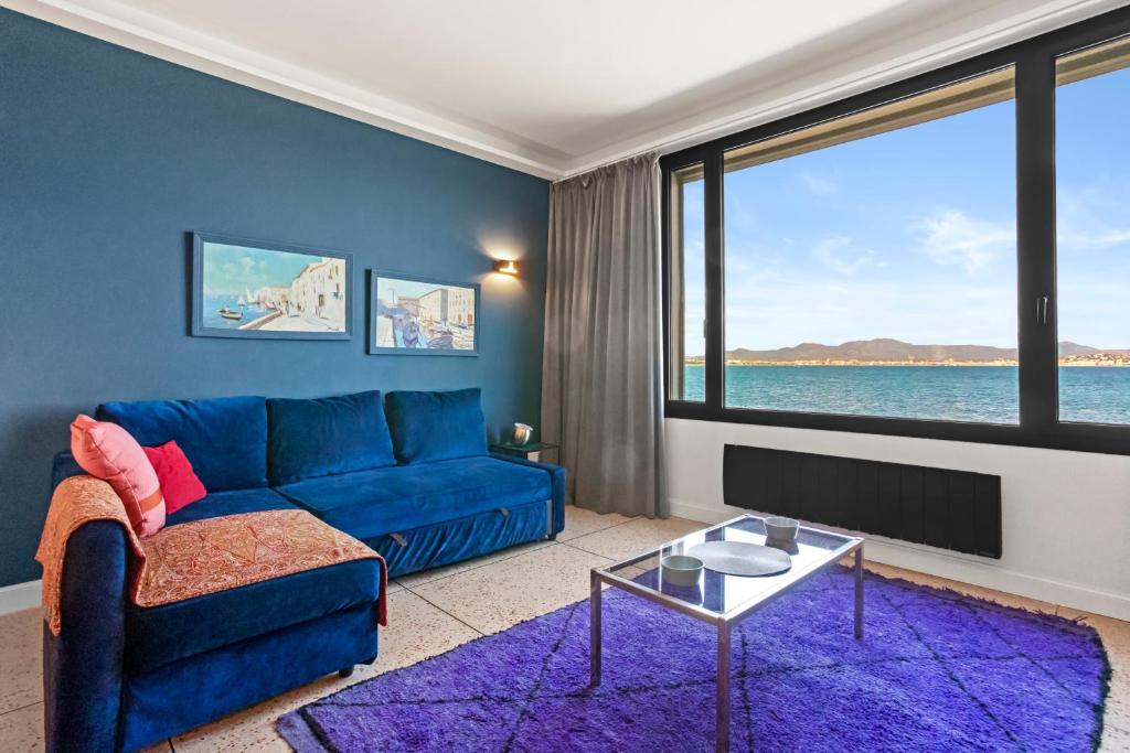 a living room with a blue couch and a large window at Exception Maison pieds dans l'eau in Fréjus