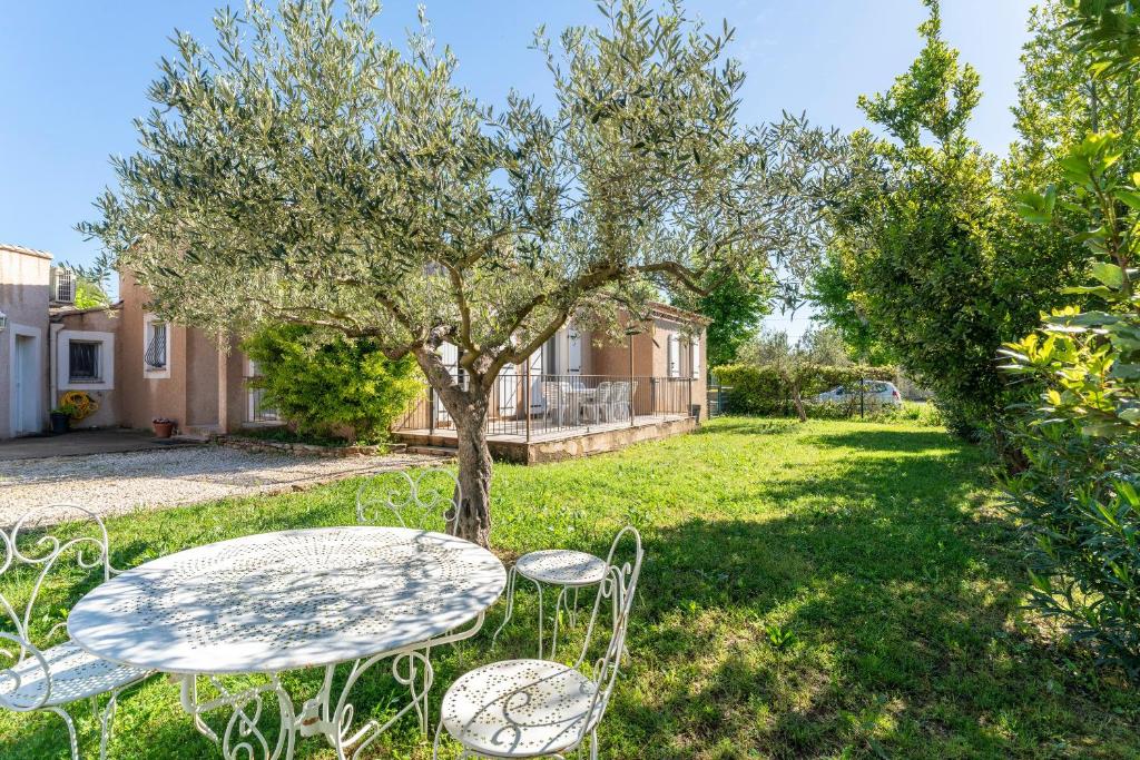 a table and chairs in a yard with a tree at Villa de Maithe, clim, terrasse in Sernhac