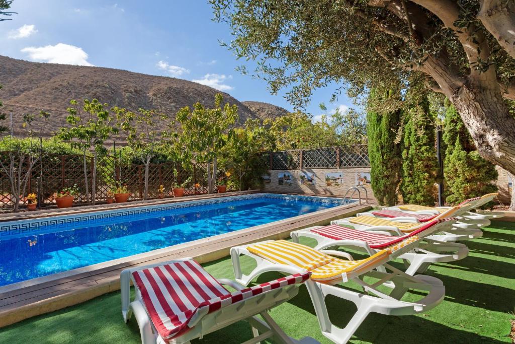 a row of lounge chairs next to a swimming pool at Villa Private Pool Los Cristianos in Los Cristianos