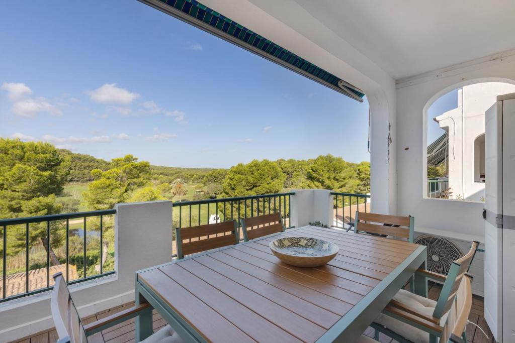 a deck with a wooden table and chairs on a balcony at Casa Golf in Son Parc