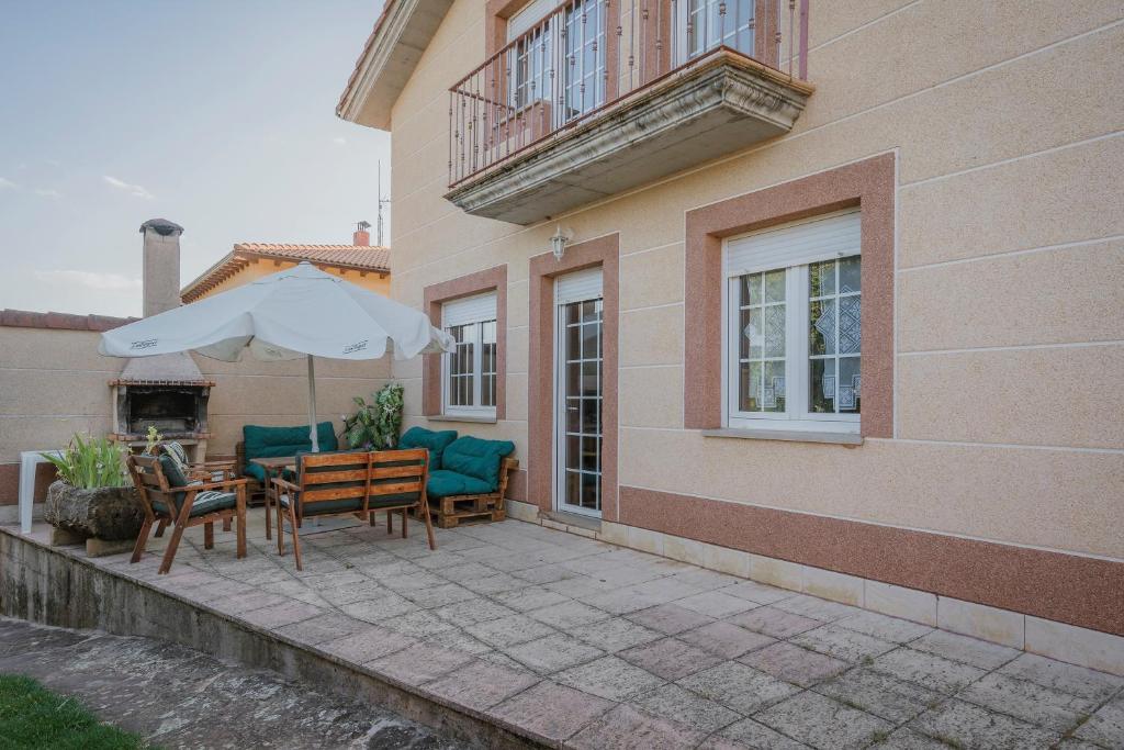 a patio with a table and chairs and an umbrella at San Pelayo in San Millán de Lara