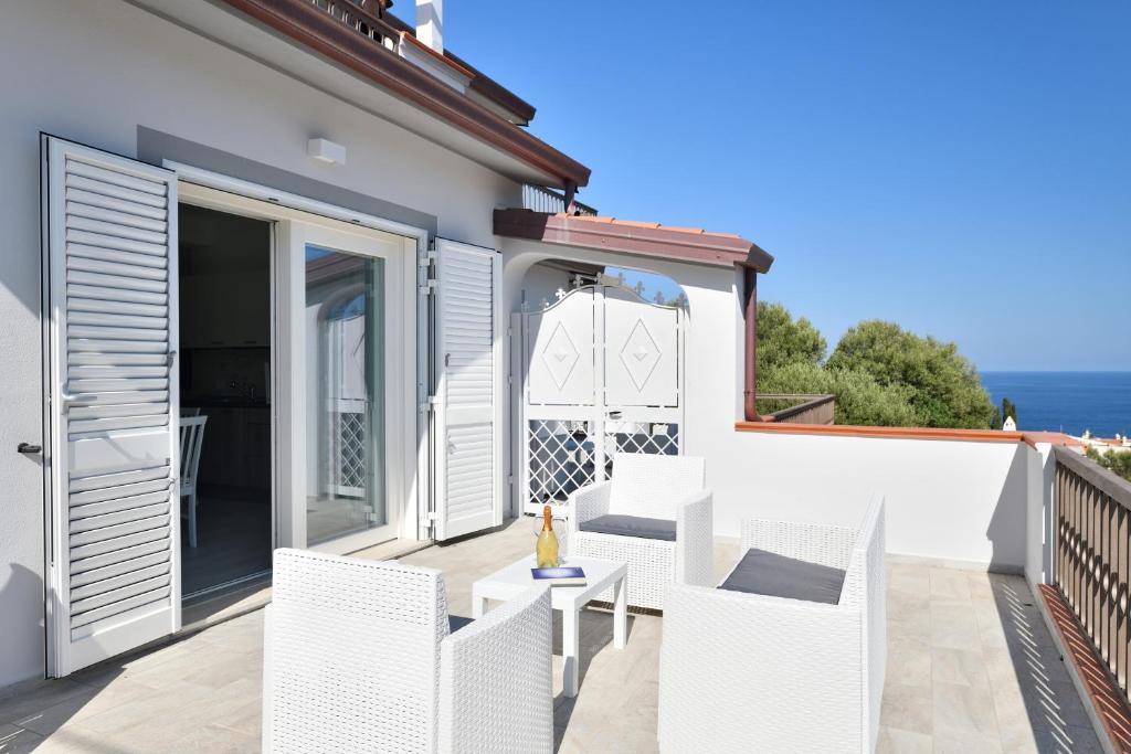 a patio with white chairs and a table on a balcony at Venere cala gonone vista mare in Cala Gonone