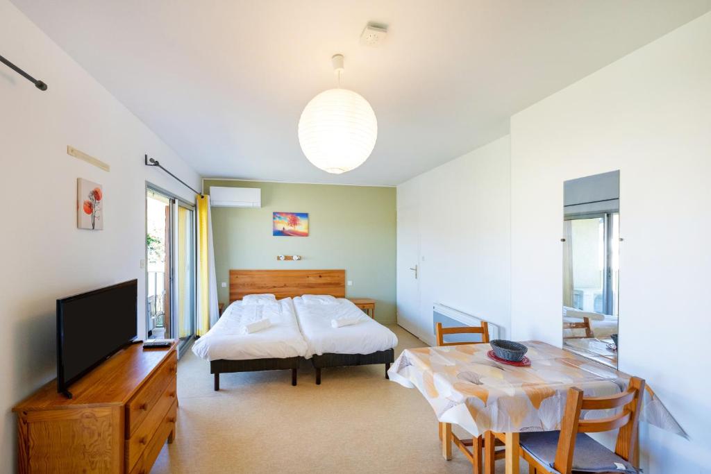 a bedroom with a bed and a table and a television at Les Mimosas - Appartement 10 in Cazaubon