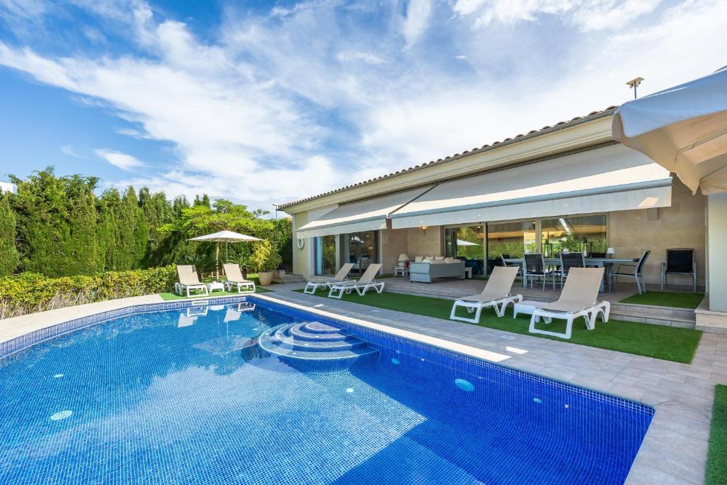 a swimming pool with chairs and a house at Villa Bellviure Luxury in Palma in Marratxí 