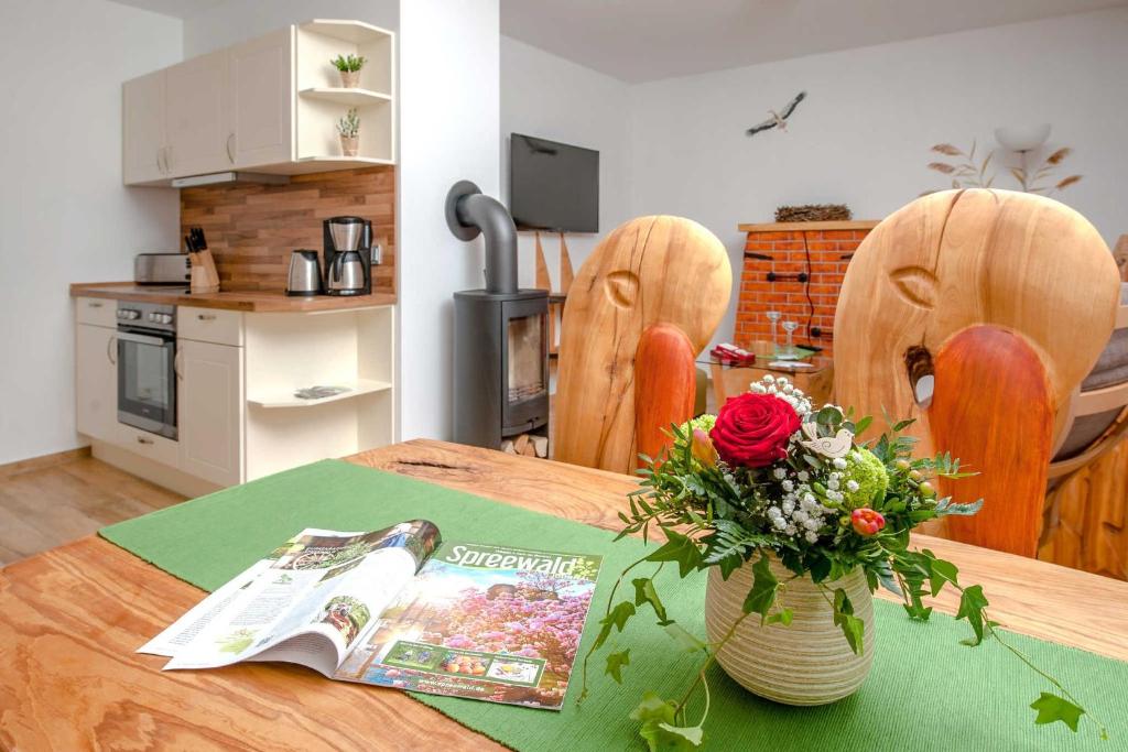 a kitchen with a table with a magazine and a vase of flowers at Ferienwohnung Storchennest in Neuendorf am See