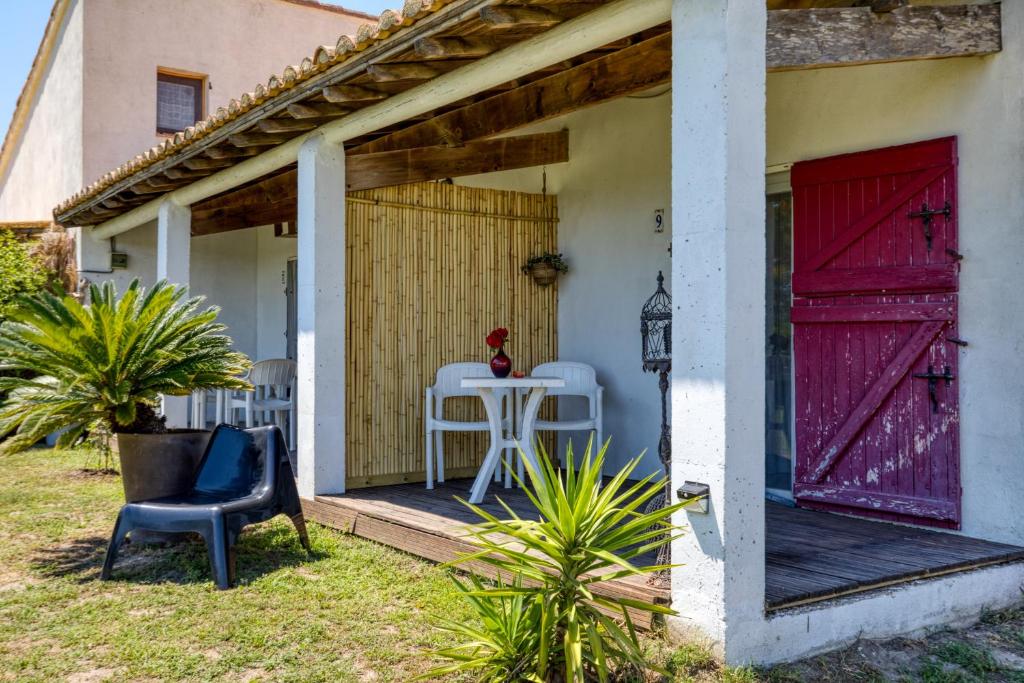 a porch with red doors and a table and chairs at Mas des Cypres - Mazet 9 in Saintes-Maries-de-la-Mer