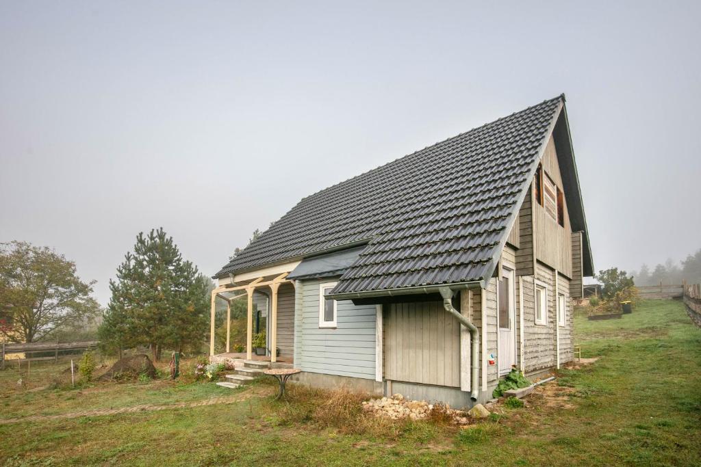 a small house with a gray roof on a field at Holzhaus am Waldrand in Niederfinow