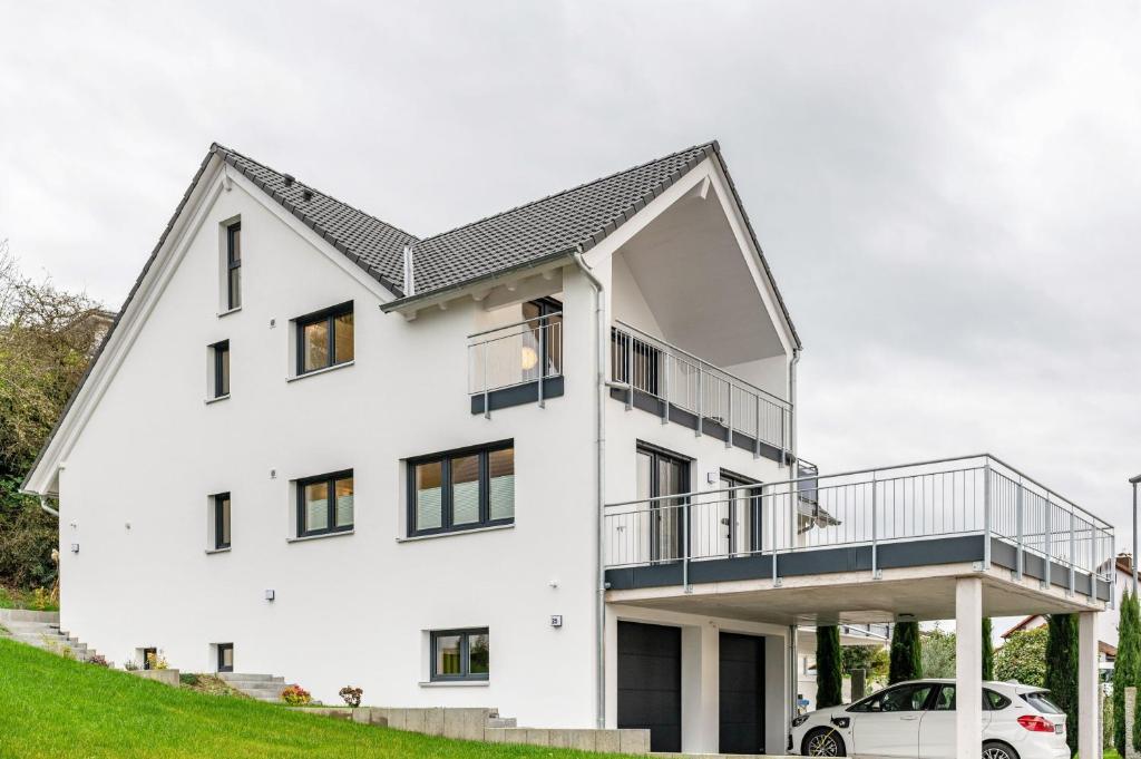 a white house with a balcony and a car at Ferienwohnung Vogesenpanorama in Bad Bellingen