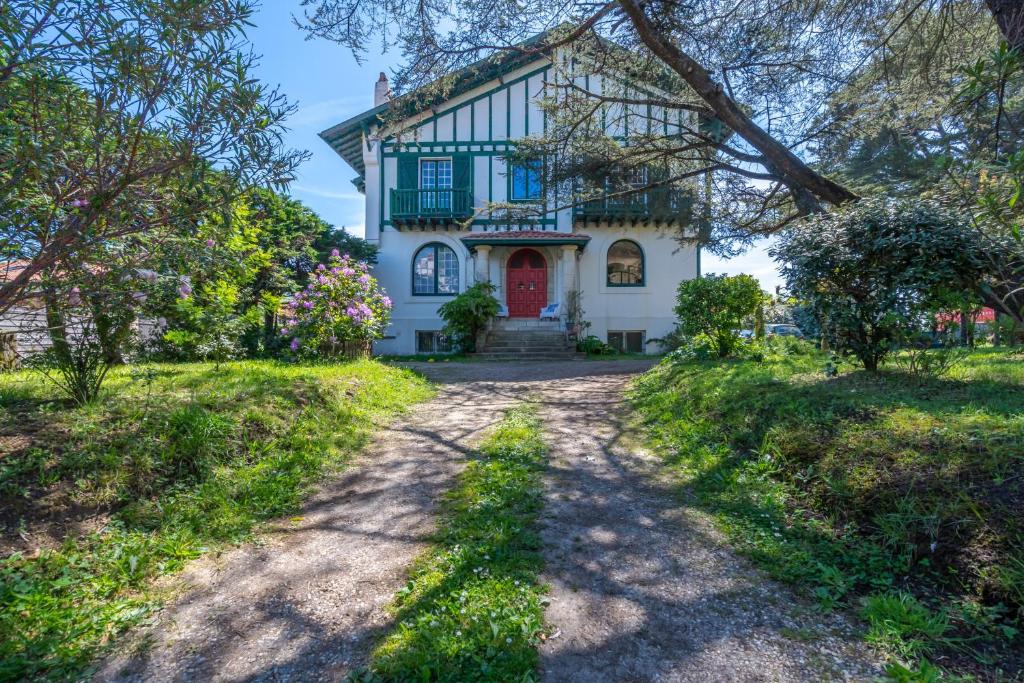 a house with a red door on a dirt road at Belle villa basque in Anglet