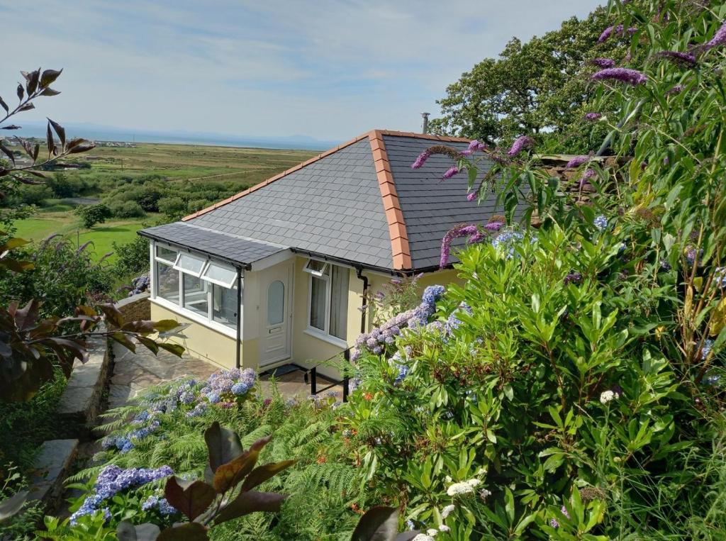 a small house with a garden and flowers at Bryn Rhedyn Fairbourne in Fairbourne