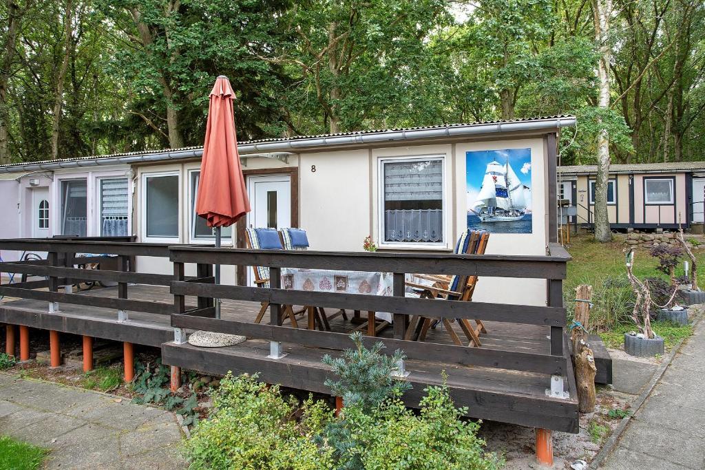 a tiny house with an umbrella sitting on a deck at Bungalow Schoner Greif, Bgl 8 in Dranske