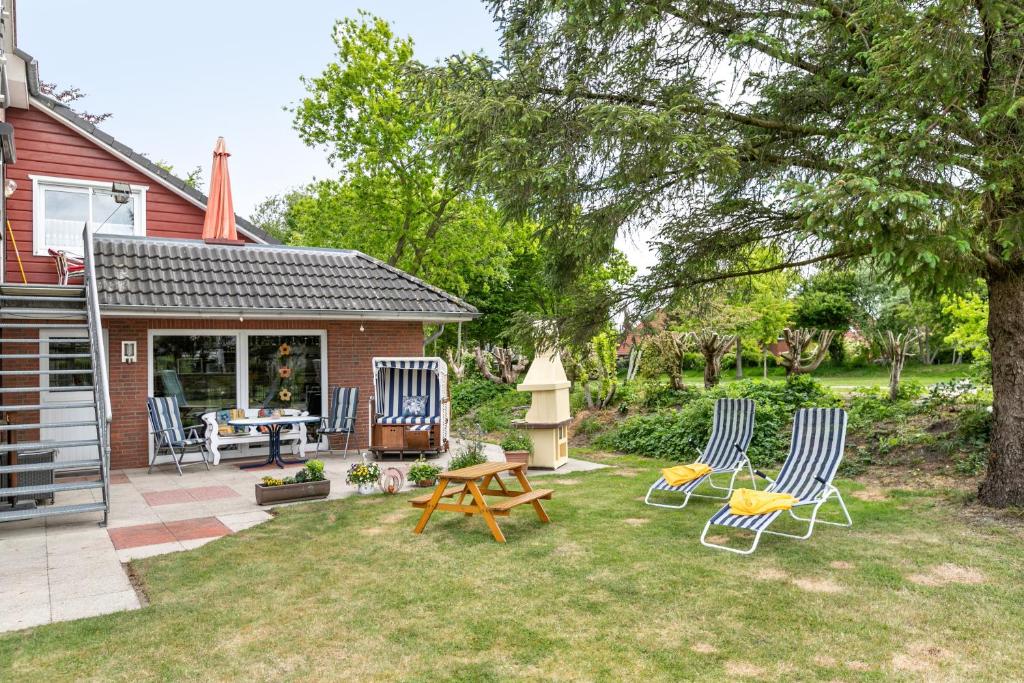 a yard with two chairs and a picnic table and a house at Gästehaus Elke Jensen in Langenhorn