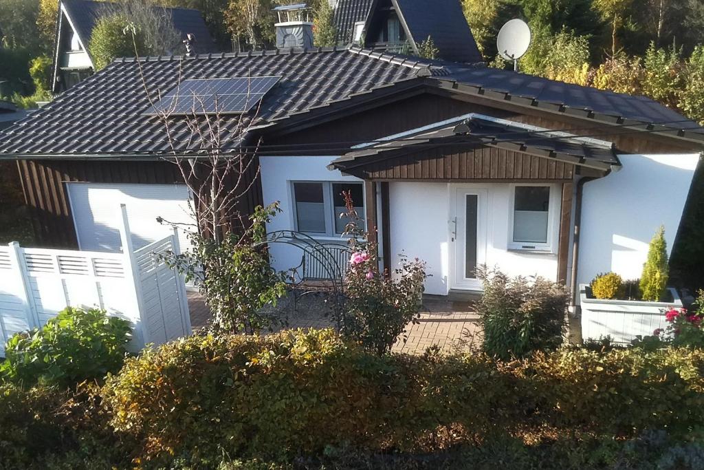 a small white house with a solar roof at Glückshuuske Sauerland in Meschede