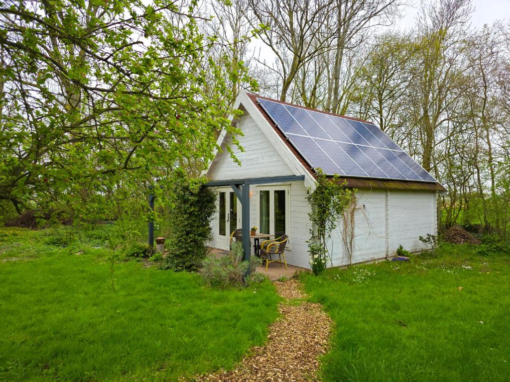 a small white house with solar panels on the roof at Vakantiewoning Moerweie GR04 in Grijpskerke