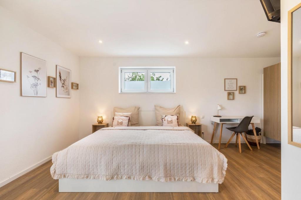 a white bedroom with a large bed and a desk at Fewo Parkside S2 - 8Min Legoland in Günzburg