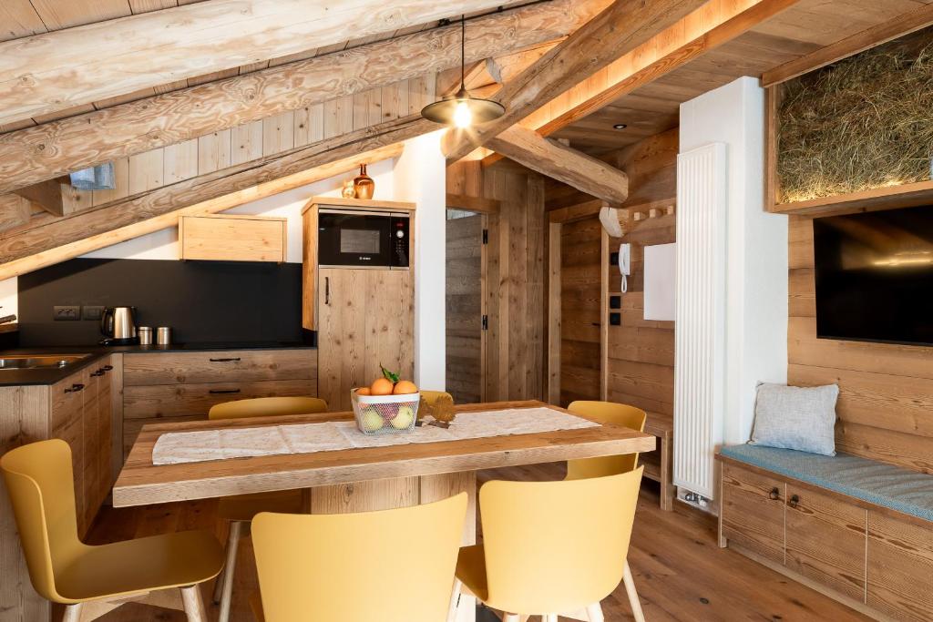 a kitchen and dining room with a table and yellow chairs at Alpine Mood Apartments in Falcade