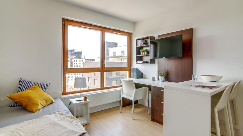a bedroom with a desk and a bed and a window at Apparteo Strasbourg in Strasbourg