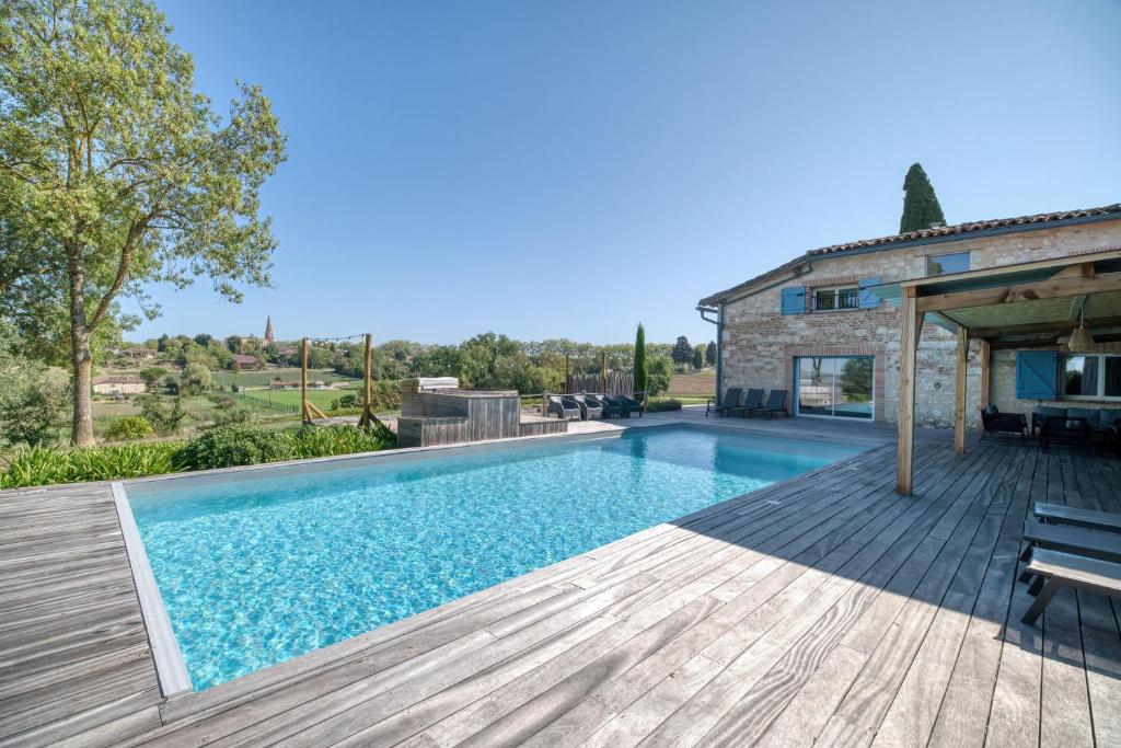 a house with a swimming pool and a wooden deck at Villa Virginie gite 2 in Faudoas