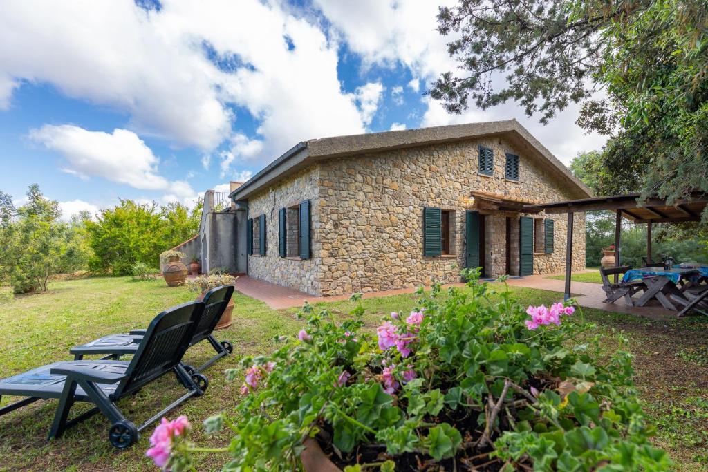 a stone house with a bench in the yard at La Sassetta in Bibbona