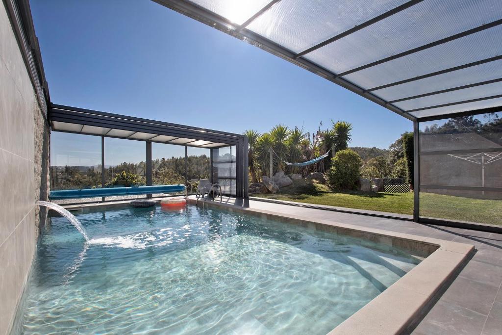 a swimming pool in a house with an umbrella at Villa Mila Piscina e Jacuzzi in Salir de Matos