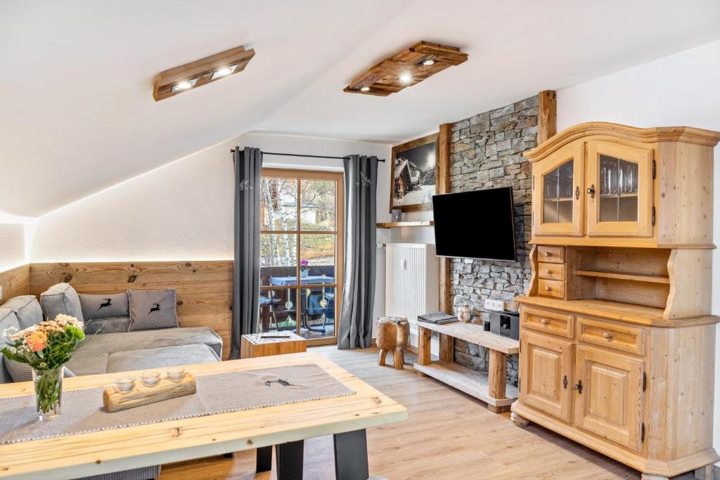 a living room with a couch and a tv at Haus Alpenquelle Seeblick in Bad Kohlgrub