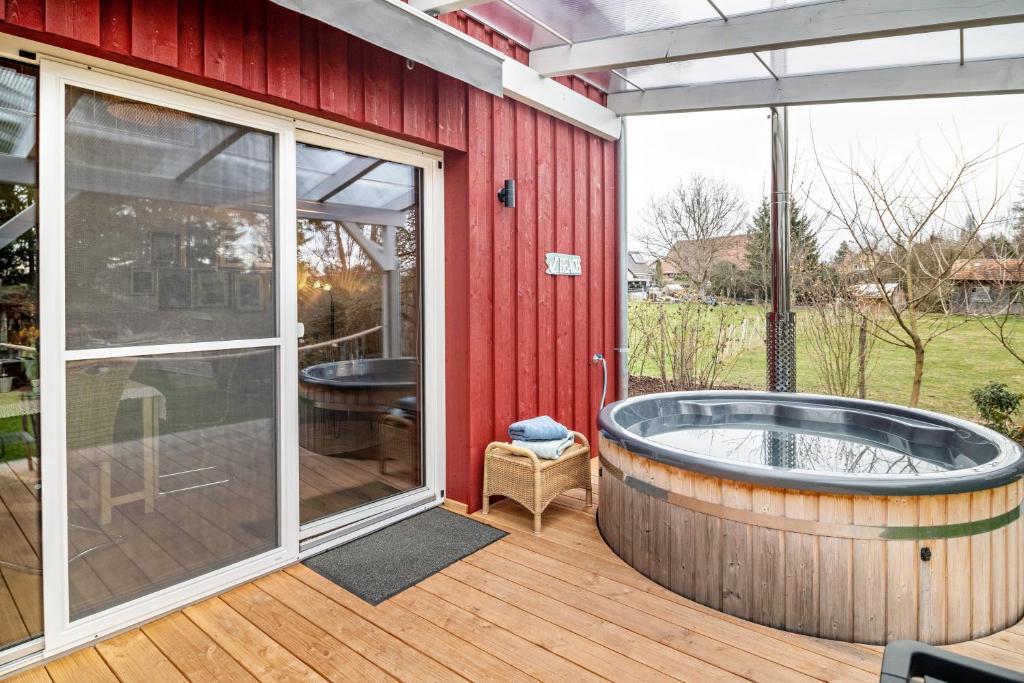 a hot tub on a deck next to a red house at Vroni in Ebersbach-Musbach